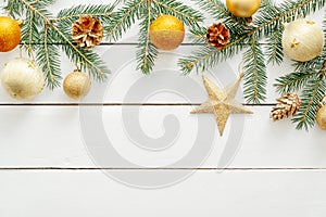 Christmas card with golden ornaments, balls, star, fir tree branches, pine cones on wooden white background. Flat lay Christmas