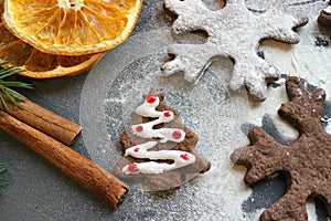 Christmas card. Homemade gingerbread in the form of Christmas trees, drenched with white glaze. Cinnamon sticks and dried orange s