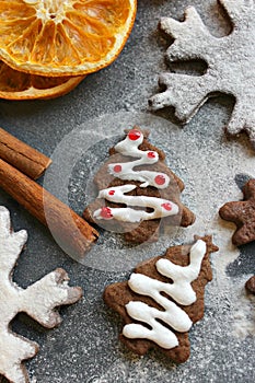 Christmas card. Homemade gingerbread in the form of Christmas trees, drenched with white glaze. Cinnamon sticks and dried orange s