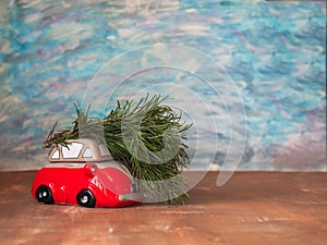 Christmas card with a little red car carrying a Christmas tree on blue and brown backgrounds