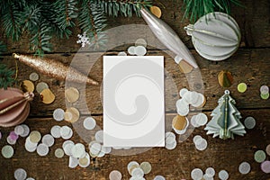 Christmas card mock up. Empty greeting card and christmas ornaments, decorations, confetti and pine branches on rustic wooden