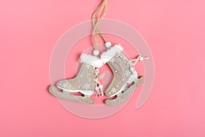 Christmas card. New year decor- red wooden skates are hung on a string on pink background