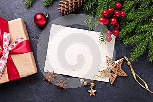 Christmas card with paper, gift box and fir tree branch on stone background. Holiday mockup. Top view