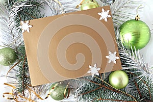 Christmas card : place for text on a silver-brown background with white snowflakes, green Christmas balls and festive tinsel, top