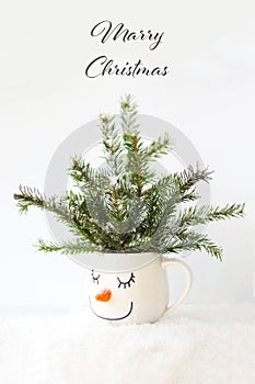 Christmas card snowy tree in a cup with the face of a sleeping snowman.