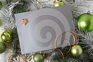 Christmas card : space for text on a silver-gray background , green Christmas balls and festive tinsel, top view