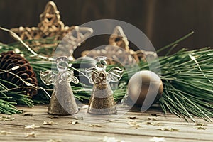 Christmas card with two angels,fir branches, decorations and a garland on a wooden background.Selective focus.Copy space