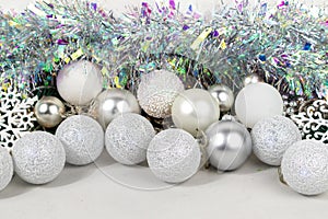 Christmas card with white and silver balls, garland, tinsel, snowflakes on a white background.