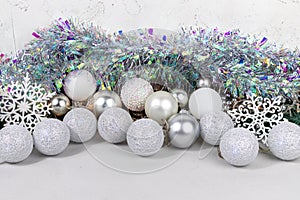 Christmas card with white and silver balls, garland, tinsel, snowflakes on a white background.