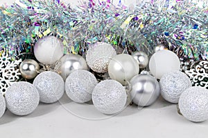 Christmas card with white and silver balls, garland, tinsel, snowflakes on a white background.