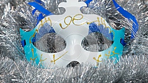 Christmas carnival mask on a silver tinsel background. Christmas masque with christmas tinsel .