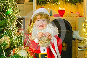 Christmas Carols. Happy boy holds a Christmas tree toy. Little cute santa claus. Christmas holiday for children.