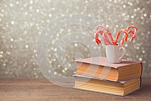 Christmas celebration with candy cane and cup on books over bokeh background