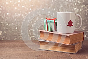 Christmas celebration with cup and gift box on books over bokeh background