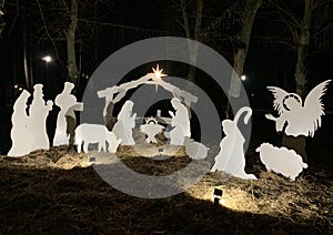 Christmas characters in a manger. Christmas decoration in the park on a dark background. Nativity scene with backlight. Concept: