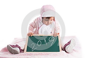 Christmas Child baby girl holding wooden blackboard with text 2019 year i