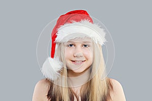 Christmas child girl in red Santa hat on gray background