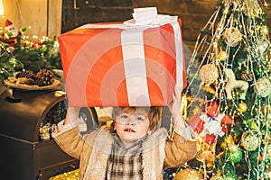 Christmas child holding a huge gift box. Happy child decorating Christmas tree. Happy cute child in Santa hat with