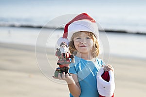Christmas child holiday concept. Santa kid on the sunset sea. Summer hot New Year. Sea background, holiday concept
