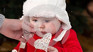 Christmas child looks at a garland with hearts. A cute little girl in a red dress and white hat. Christmas concept of kindness,
