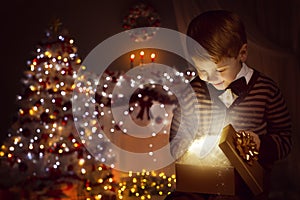 Christmas Child Open Present Gift Box, Happy Kid Opening Giftbox in Xmas Tree Home Interior photo