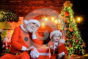Christmas child in Santa hat and Santa Claus with Christmas gift at home. Santa Claus and little boy with Christmas
