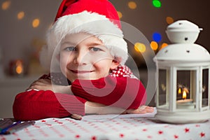 Christmas child writing letter to Santa in red hat