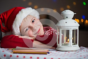 Christmas child writing letter to Santa in red hat