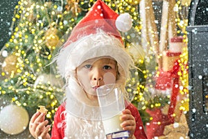 Christmas childs in snow. Happy kids Santa Claus with glass of milk and cookie. Santa Claus eating cookies and drinking