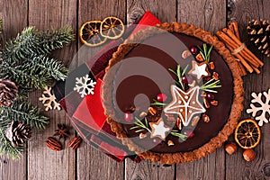 Christmas chocolate gingerbread tart. Above view table scene over rustic wood.