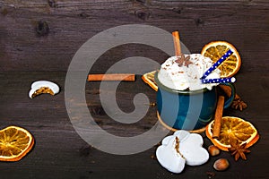 Christmas coffee cup with whipped cream, cinnamon, cocoa powder, anise, dried orange ang gingerbread cookies