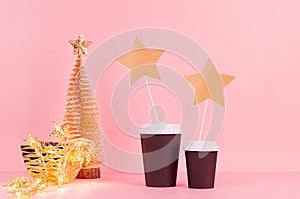 Christmas coffee mock up - gold Christmas tree, lights, blank tage with black paper cups on pink background, template.