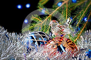 Christmas decorations lying in tinsel and fir branches on a dark background with blurred lights