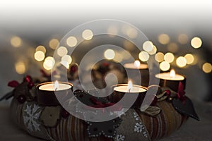 Christmas is coming with Advent. Beautiful closeup of burning candles of Advent wreath and golden Christmas lights on background