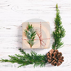 Christmas composition background. Christmas gift with pine cones and fir branches on wooden background. Flat lay, top view, copy