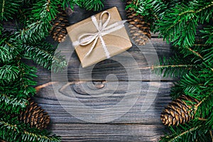 Christmas composition background. Christmas gift with pine cones and fir branches on wooden background. Flat lay, top view, copy