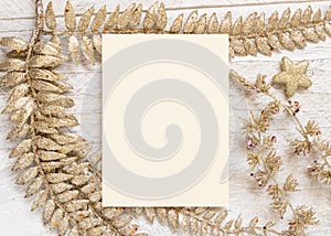 Christmas composition with Blank greeting card and golden leaves on white wooden table