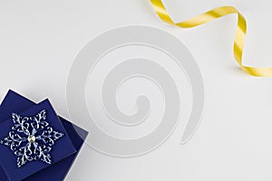 Christmas composition with blue box, snowflake and yellow ribbon on white background