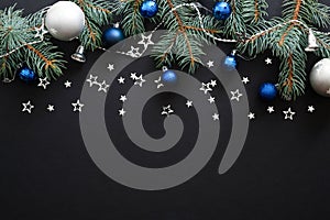 Christmas composition with blue and sliver modern decorations, baubles, fir tree branches on dark black background. Elegant