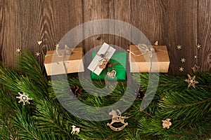 The border is made of gift boxes, pine branches, cones, wooden decorative toys, snowflakes and stars on a wooden background. Chris