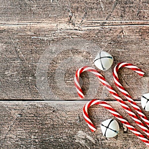 Christmas composition of Candy Canes and Jingle Bells on Brown Wood