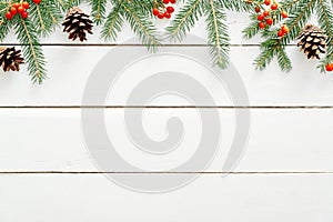 Christmas composition. Christmas frame made of fir tree branches, red berry, gift boxes, cones on wooden white background. Flat