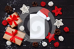 Christmas composition. Christmas gifts and notepad with decor on wooden black background. Top view, flat lay, copy space