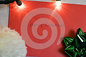 Christmas composition. Christmas hat, green bow, and an envelope with Merry Christmas written on it