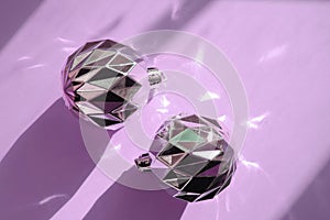 Christmas composition. Christmas silver balls decorations on pastel purple  background with beautiful festive reflections of light