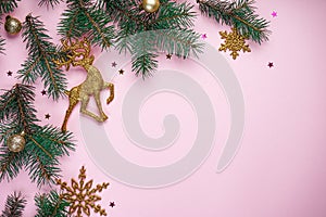 Christmas composition. Christmas tree branches, with New Year`s gold ornaments and multi-colored sweets on a pink background.