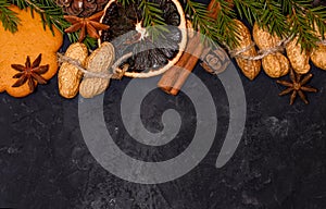 Christmas composition with cinnamon, nuts, cookies and spices on black background, with green spruce tree branch Flat lay