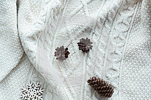 Christmas composition with cone, snowflakes on white knitted sweater. Holiday card. Vintage style. Flat lay.