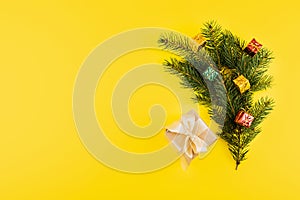 Christmas composition with Conifer Evergreen tree branches and gift box on yellow background. Christmas and 2020 new year minimal