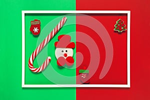 Christmas composition with decorative snowman, lollipop on red and green background with white frame. Winter holiday concept